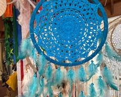 Bright turquoise dreamcatcher with intricate crochet center and long feathered tassels. Beautiful boho wall décor perfect for bedrooms, patios, or artistic hanging displays.