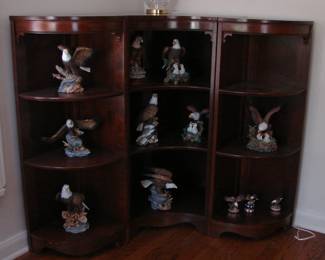 Curvy three section corner cabinet brimming with bisque eagles.