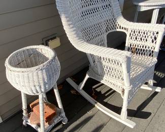The porch is full of classic white wicker, and planters.