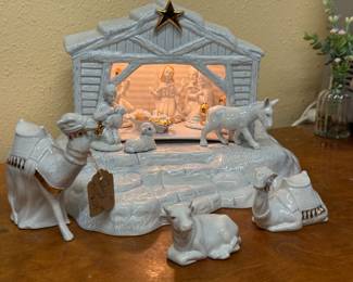 White porcelain nativity set with stable structure and gold star on top with light