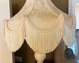 Victorian-style table lamp with an ivory brocade fringed bell shade and white marble base.
