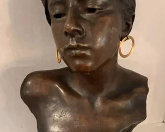 Stunning signed bronze bust by renowned French sculptor Emmanuel Villanis (1858-1914), known for his expressive Art Nouveau portrayals of women. This elegant piece depicts a woman with graceful features, wearing large hoop earrings and a draped headscarf. The figure is believed to represent one of Villanis' celebrated subjects-possibly a gypsy or Egyptian woman-symbolizing beauty, mystery, and strength. The piece stands approximately 21" H and rests on a patinated bronze base with Egyptian-style motifs.
Villanis was one of the most recognized sculptors of the late 19th and early 20th centuries, celebrated for his lifelike bronze busts cast by leading Paris foundries. His works remain highly sought after by collectors for their fine craftsmanship, delicate emotion, and connection to the Art Nouveau era. This example bears his signature on the shoulder and displays a rich aged patina that enhances its timeless allure. A striking centerpiece for any art or sculpture collection.