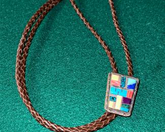 Native American-style Sterling silver bolo tie featuring a multi-stone inlay pendant on a braided leather cord.
