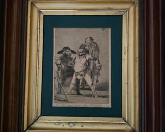 This is a framed etching by Francisco Goya. The image depicts a scene with several figures, characteristic of Goya's "Caprichos" series, which satirizes the follies and vices of Spanish society. The etching itself appears to be in good condition, with clear lines and detail. The frame is ornate and appears to be made of wood with a gilded finish, suggesting it is of some age. The matting is a deep green, providing a strong contrast to the monochromatic print.