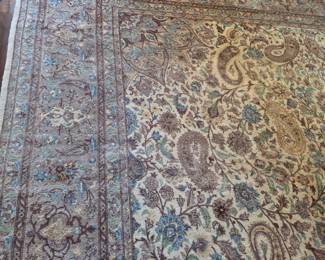 This is a finely woven Persian rug featuring a classic paisley (boteh) motif. The intricate design is characteristic of traditional Persian carpet making, likely originating from regions renowned for their textile artistry such as Tabriz, Kerman, or Isfahan. The color palette is muted, dominated by creams, blues, browns, and greens, suggesting a mature aesthetic. The rug appears to be made from wool, a common material for Persian rugs, known for its durability and softness. The presence of a detailed border with floral and geometric patterns frames the central field, enhancing its overall elegance. The fringe on one side appears to be intact, indicating good overall condition, though a professional cleaning might be beneficial to revive its original luster.