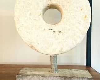 antique millstone disc on a stand, also known as a threshing wheel.