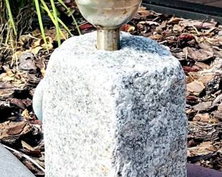 solar-powered garden light with a globe top, mounted on a stone base