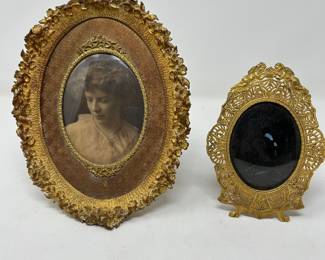 Antique ornate gilt picture frame containing an oval portrait photo of woman, 8.5"H,  $34.  Antique oval frame with cherubs on top, 5.5"H,  $25 .