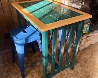 a breakfast or side table. Mission or Arts and Crafts-style pub table with green ceramic tile top and a wooden frame and legs, blue metal stools