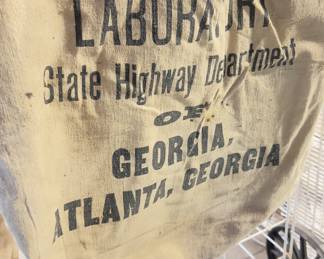canvas bag with faded black text printed on it. The text identifies the bag's origin and purpose.
LABORATORY
State Highway Department OF GEORGIA
ATLANTA, GEORGIA