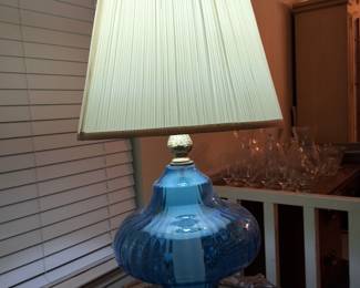 Set of 2 blue glass table lamps with off-white shades.