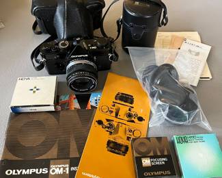 Olympus camera with accessories and manuals.