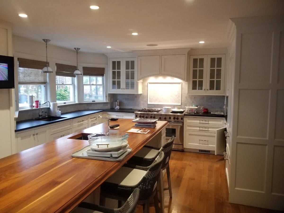 White modern farmhouse kitchen by Quality Custom Cabinetry. Kitchen is U-shaped with a long island. Pendant lights