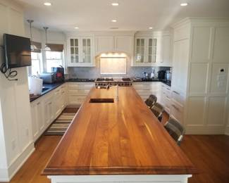 White modern farmhouse kitchen by Quality Custom Cabinetry. Kitchen is U-shaped with a long island. Pendant lights; Wood-Mode cabinets