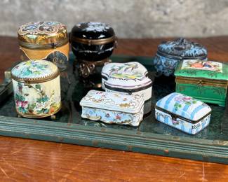 This lot features a large collection of antique trinket boxes that are primarily porcelain. Many of them contain maker marks and are held on a vintage green tray that is included.