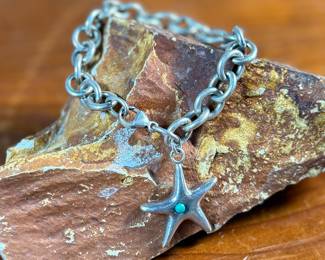 This lot features a sterling silver starfish charm bracelet with an inlay stone by designer, Elsa Peretti for Tiffany & Co. This bracelet measures 7” and has a total approx. weight of 34.32 grams.
