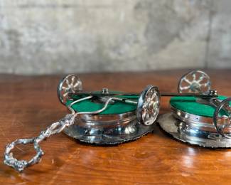 This lot features an antique Victorian silver plated wine coaster trolley made in Japan along with a sterling silver wine coaster by Frank Whiting & Co.