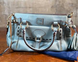 This lot features a Dooney & Bourke Florentine Satchel bag in blue Italian leather. This Dooney & Bourke comes with the original carry case as shown in photos and is in excellent condition.