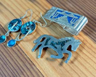 This lot features a collection of Alpaca silver jewelry featuring a horse pin/brooch, a pair of earrings, and a money clip. All items are marked Alpaca as shown in photos and have a total approx. weight of 50.14 grams.