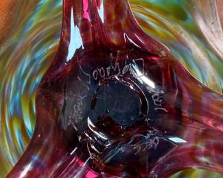 This lot features a stunning studio made footed glass bowl by listed artist, Mark Woodham. Signed and dated underneath and was made during Woodham’s time creating works at the One Eared Cow Glass Studio. This bowl measures, 5” H x 9” W x 9” D and is in excellent condition.