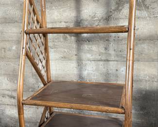 This lot features a vintage rattan shelving unit with two glass shelves on the top two tiers. This unit measures, 71.5” H x 29.5” W x 19.5” D.