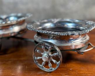 This lot features an antique Victorian silver plated wine coaster trolley made in Japan along with a sterling silver wine coaster by Frank Whiting & Co.