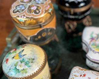 This lot features a large collection of antique trinket boxes that are primarily porcelain. Many of them contain maker marks and are held on a vintage green tray that is included.