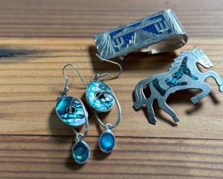 This lot features a collection of Alpaca silver jewelry featuring a horse pin/brooch, a pair of earrings, and a money clip. All items are marked Alpaca as shown in photos and have a total approx. weight of 50.14 grams.