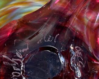 This lot features a stunning studio made footed glass bowl by listed artist, Mark Woodham. Signed and dated underneath and was made during Woodham’s time creating works at the One Eared Cow Glass Studio. This bowl measures, 5” H x 9” W x 9” D and is in excellent condition.