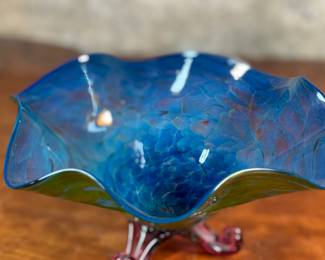 This lot features a stunning studio made footed glass bowl by listed artist, Mark Woodham. Signed and dated underneath and was made during Woodham’s time creating works at the One Eared Cow Glass Studio. This bowl measures, 5” H x 9” W x 9” D and is in excellent condition.