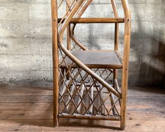 This lot features a vintage rattan shelving unit with two glass shelves on the top two tiers. This unit measures, 71.5” H x 29.5” W x 19.5” D.