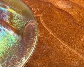 This lot features an iridescent gold Tiffany Favrile sherbet glass with maker marks present underneath as shown in photos. One small repair on the foot ring and measures, 3.5” H x 4” W x 4” D.