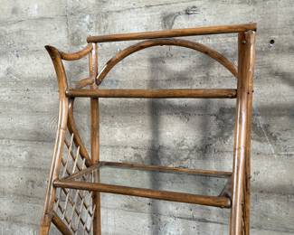 This lot features a vintage rattan shelving unit with two glass shelves on the top two tiers. This unit measures, 71.5” H x 29.5” W x 19.5” D.