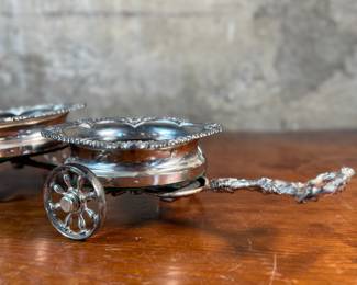 This lot features an antique Victorian silver plated wine coaster trolley made in Japan along with a sterling silver wine coaster by Frank Whiting & Co.
