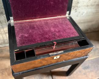 This lot features a 19th century burled walnut writing slope on a lacquered stand. The burled walnut top has a central brass inlaid presentation plaque that is inscribed. This piece measures (on stand), 18” H x 15.5” H x 11” D.