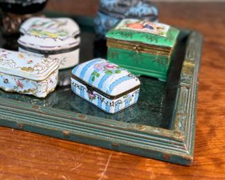 This lot features a large collection of antique trinket boxes that are primarily porcelain. Many of them contain maker marks and are held on a vintage green tray that is included.