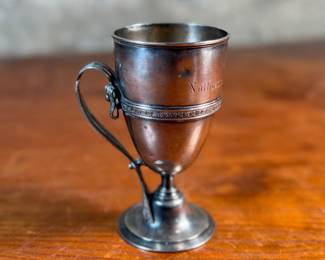 This lot features a 1873 birth commemorative sterling silver footed cup retailed by Ohio jeweler & silversmith, William Wilson McGrew (1833-1893). This silver cup was made to commemorate the birth of Nathaniel Foster Wilshire, son of George Wilshire who was a railroad and business tycoon. This cup measures, 5.25” H x 2.75” W x 4” D with a total approx. weight of 176.61 grams. Maker marks present underneath as shown in photos.