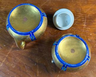 This lot features an antique sugar bowl with lid and a cream pitcher set, hand-painted in an Art Nouveau style by an artist named Osborne for Pickard China. The set features a design with stylized flowers on a cobalt ground and multiple borders of blue and white luster colors.