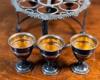 This lot features an antique silver-plated Victorian egg cruet set with six egg cups. This cruet measures, 9” H x 7.5” W x 7.5” D.