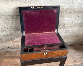 This lot features a 19th century burled walnut writing slope on a lacquered stand. The burled walnut top has a central brass inlaid presentation plaque that is inscribed. This piece measures (on stand), 18” H x 15.5” H x 11” D.