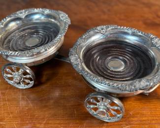 This lot features an antique Victorian silver plated wine coaster trolley made in Japan along with a sterling silver wine coaster by Frank Whiting & Co.