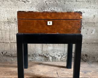 This lot features a 19th century burled walnut writing slope on a lacquered stand. The burled walnut top has a central brass inlaid presentation plaque that is inscribed. This piece measures (on stand), 18” H x 15.5” H x 11” D.