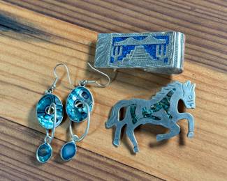 This lot features a collection of Alpaca silver jewelry featuring a horse pin/brooch, a pair of earrings, and a money clip. All items are marked Alpaca as shown in photos and have a total approx. weight of 50.14 grams.