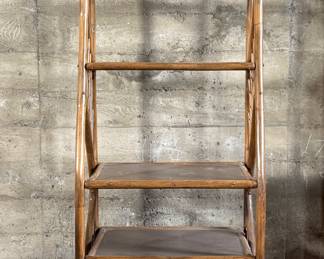 This lot features a vintage rattan shelving unit with two glass shelves on the top two tiers. This unit measures, 71.5” H x 29.5” W x 19.5” D.