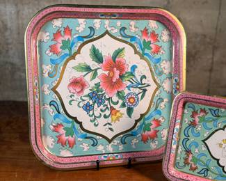 This lot features a collection of four (4) pieces of Daher Decorative Ware including two trays & two tin boxes. The largest tray measures, 13.75” H x 13.75” W. Daher’s most recognizable tins are decorated with detailed floral and geometric designs, rich in color, and often including metallic inks and raised or embossed relief. In addition to tin boxes, Daher also produced trays, plates, plaques, and other assorted tin ware for practical and decorative use.