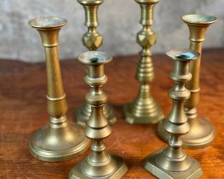 This lot features a collection of six (6) antique brass candlesticks. Three matching pairs with the tallest measuring, 9.5” H.