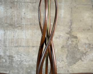 This lot features a mid-century modern sculptural table lamp, made of walnut and brass. Minor wear throughout as shown in photos and light turns on periodically (will need to some servicing or love). This lamp measures, 38” H x 7” W x 7” D.