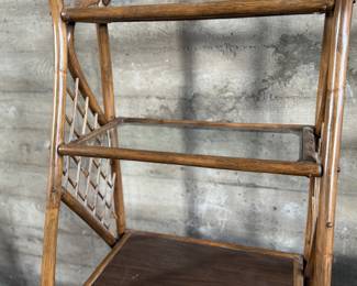 This lot features a vintage rattan shelving unit with two glass shelves on the top two tiers. This unit measures, 71.5” H x 29.5” W x 19.5” D.