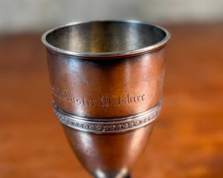 This lot features a 1873 birth commemorative sterling silver footed cup retailed by Ohio jeweler & silversmith, William Wilson McGrew (1833-1893). This silver cup was made to commemorate the birth of Nathaniel Foster Wilshire, son of George Wilshire who was a railroad and business tycoon. This cup measures, 5.25” H x 2.75” W x 4” D with a total approx. weight of 176.61 grams. Maker marks present underneath as shown in photos.