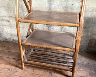 This lot features a vintage rattan shelving unit with two glass shelves on the top two tiers. This unit measures, 71.5” H x 29.5” W x 19.5” D.